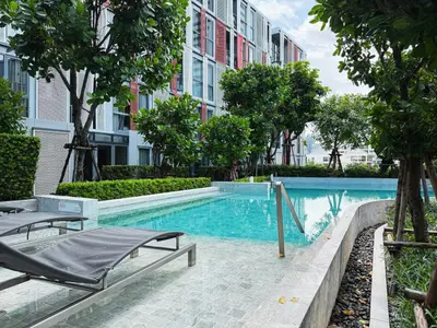 a swimming pool with two lounge chairs next to a building at Near BTS l Workspace and Kitchen - Pool and Gym l Sontana in Bangkok
