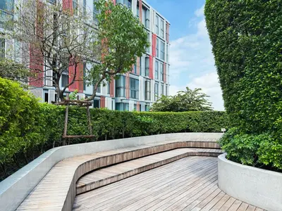 a bench in front of a building with bushes at Near BTS l Workspace and Kitchen - Pool and Gym l Sontana in Bangkok