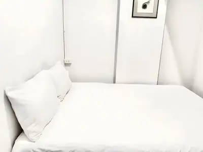 a bed with white sheets and pillows in a room at x Mirt Inn Sukhumvit II - ถนนสุขุมวิท 2 in Bang Kapi
