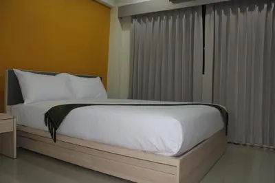 a bed with white sheets and pillows in a bedroom at La Porte Hotel Bangkok in Bangkok