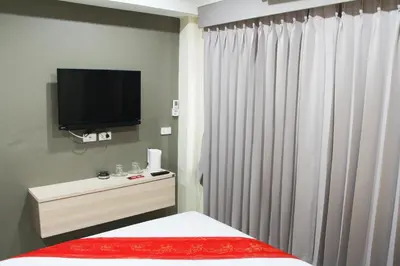 a bedroom with a bed and a tv and curtains at La Porte Hotel Bangkok in Bangkok