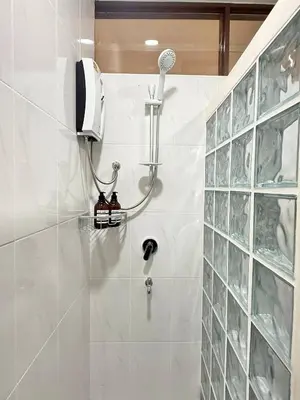a shower in a white tiled bathroom at Spacious CityCentre | 500 mbps, King-size, Balcony in Khlong Toei