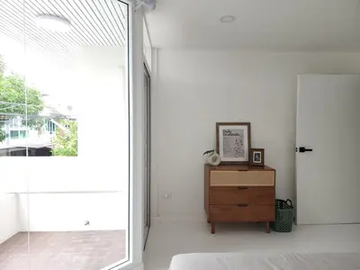 a bedroom with a bed and a window and a dresser at White House Ekkamai in Bangkok