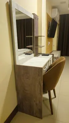 a bathroom with a vanity with a mirror and a chair at indra apartments in Bangkok