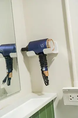 a hair dryer hanging on a wall next to a mirror at Cozy 3BR for 8 People, 5Mins from MRT Huai Khwang in Bangkok