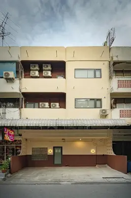 a tall yellow building with two floors and two cars at Cozy 3BR for 8 People, 5Mins from MRT Huai Khwang in Bangkok