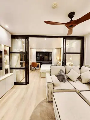 a living room with a couch and a ceiling fan at คอนโดสุขุมวิทสวีท เรียบหรู อบอุ่น ครบครัน in Makkasan
