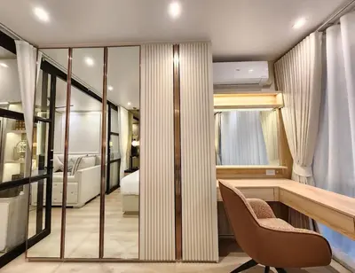 a room with a bed and a desk and chairs at คอนโดสุขุมวิทสวีท เรียบหรู อบอุ่น ครบครัน in Makkasan