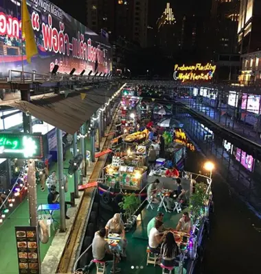 a group of people sitting at tables in a market at night at The Little Apartment in Bangkok