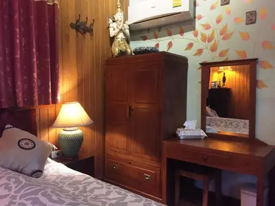 a bedroom with a bed and a dresser and a dresser with a lamp at Shanti Lodge Bangkok in Bangkok