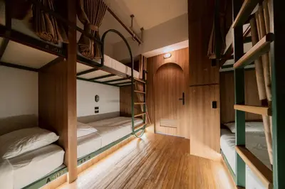 a room with three bunk beds and a wooden floor at กรุงไทย โฮสเทล สเตชั่น in Thonhuri