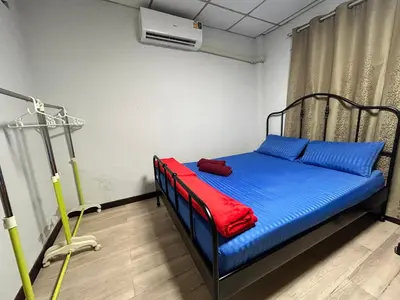 a room with a bed with blue sheets and a fan at Wewash Room Laksi - Donmuang Airport ห้องวีวอช หลักสี่ -สนามบินดอนเมือง in Thung Si Kan