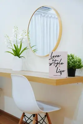 a mirror on a shelf with a white chair and a sign at Cozy KingsizeBed เจริญนคร