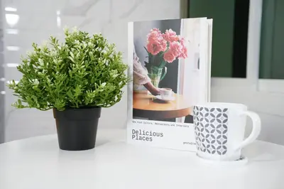 a table with a plant and a book and a cup at Cozy KingsizeBed เจริญนคร