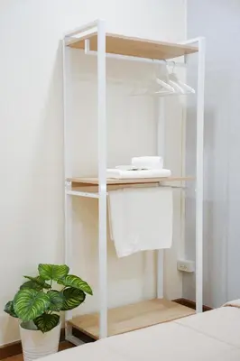 a white book shelf with a phone and a plant at Cozy KingsizeBed เจริญนคร