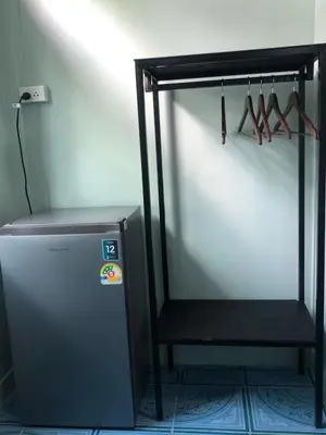 a refrigerator in a room with a rack with hangers at TongmuanHomestay&Bar in Bangkok Noi