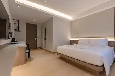 a bedroom with a large white bed and a desk at The Bentley Hotel in Bangkok