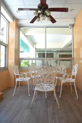 a dining room with white chairs and a ceiling fan at KT MANSION Victory Monument in Bangkok