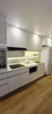 a kitchen with white cabinets and a sink and a refrigerator at Your Urban Oasis in the Heart of Sukhumvit in Bangkok