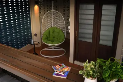a porch with a green chair and a table at Pillow & Paper in Bangkok