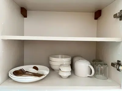 a kitchen shelf with white bowls and utensils at Stay in near International airport in Bangkok