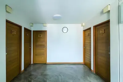 a hallway with wooden doors and a clock on a wall at XX GO INN Khaosan โก อินน์ ตรอกข้าวสาร in Bang Bua Thong Railway Station