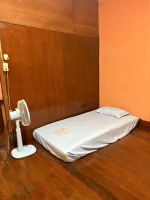 a bed in a room with a fan next to it at best 148 train staytion in Godown