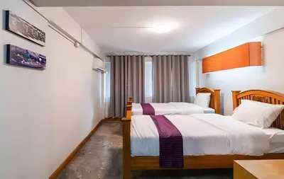 a bedroom with two beds and a table at GO INN Khaosan Chakraphong โก อิน ตรอกข้าวสาร Pro in Bang Bua Thong Railway Station