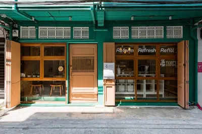 a green building with wooden doors and windows at TermSuk Apt- Banthat Thong in Bangkok