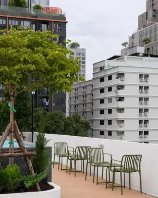 a row of chairs and tables on a balcony with buildings at Hotel PaPa Ratchada-Huai Khwang in Bangkok