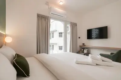 a white bedroom with a large bed and a window at Hotel PaPa Ratchada-Huai Khwang in Bangkok