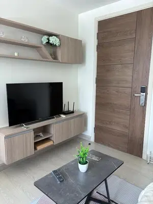 a living room with a television and a wooden door at Sukhumvit 50 apartment in Bangkok