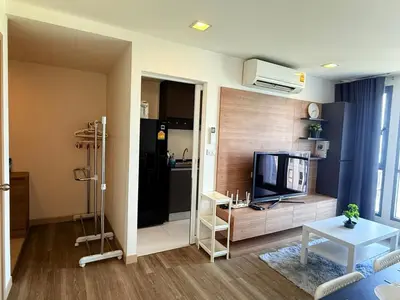a living room with a television and a kitchen at The Monti Condo in Bangkok