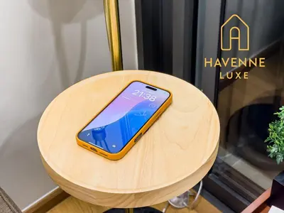 a cell phone sitting on top of a wooden table at City Luxe Condo 5-Min Walk to Siam Paragon Modern Stay in Bangkok