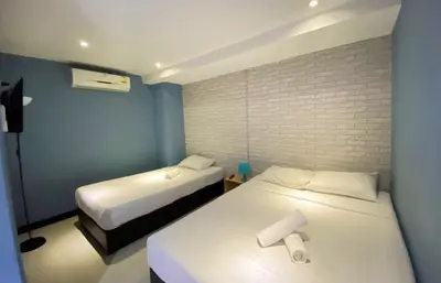 a bedroom with two beds and a brick wall at The Little Pig Sukhumvit in Bangkok