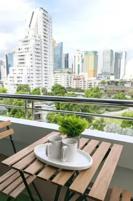 a table with two cups and a plant on a balcony at New Renovated 2 Beds Amazing Balcony View Nana BTS in Bangkok