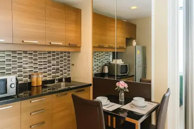 a kitchen with a table with chairs and a microwave at The Wooden Nest Warm Stay at Sukhumvit 8 in Bangkok