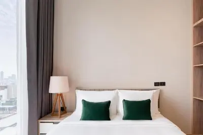 a bedroom with a white bed with green pillows at Urban Oasis BTS Ekkamai in Khlong Toei