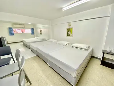 two beds in a room with a table and chairs at Bangkok-Pratunam Hotel in Bangkok
