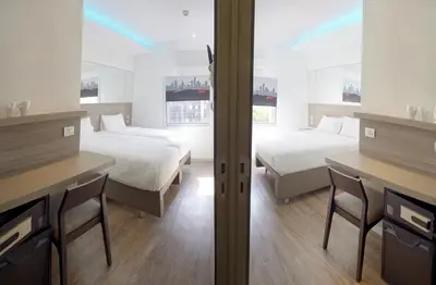 a bedroom with two beds and a desk with chairs at Easy Planet Bangkok Surawong in Bangkok