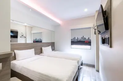 two beds in a hotel room with a tv at Easy Planet Bangkok Surawong in Bangkok