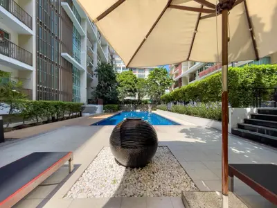a building with an umbrella and a swimming pool at Near BTS l Fully Furnished l Pool and Gym in Bangkok