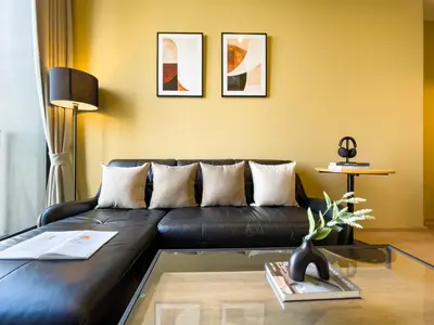 a living room with a black leather couch at Near BTS l Large 50 sqm l Luxury facilities l Rooftop Pool in Bangkok