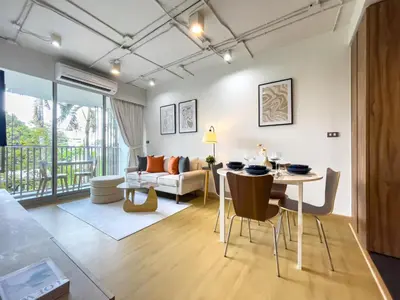 a living room with a table and chairs and a couch at Near BTS Asok and MRT SKV l Pool and Sauna in Bangkok