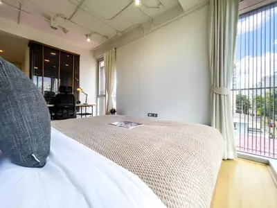 a bedroom with a bed and a large window at Near BTS Asok and MRT SKV l Pool and Sauna in Bangkok