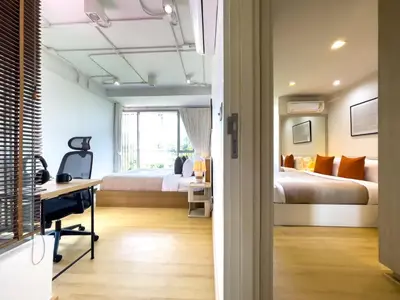 a bedroom with two beds and a desk and a room with two beds at Near BTS Asok and MRT SKV l Pool and Sauna in Bangkok