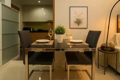 a dining room with a table with chairs and wine glasses at Cozy High-Rise Escape in the heart of Bangkok! in Bangkok