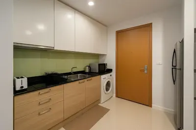 a kitchen with a sink and a washer and dryer at Cozy High-Rise Escape in the heart of Bangkok! in Bangkok