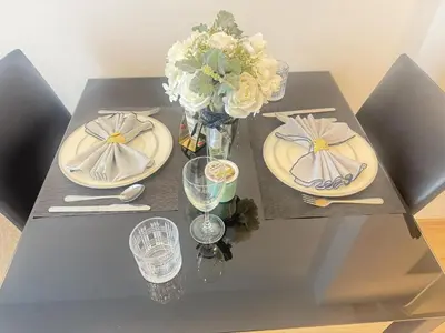 a table with two plates and a vase of flowers at Cozy&Bright apartment -Onnut BTS in Bangkok