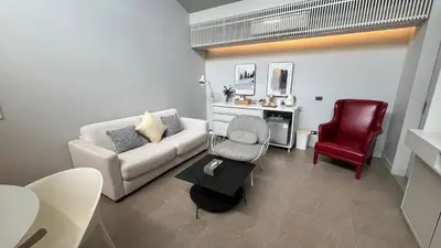 a living room with a couch and a red chair at Tree Villa Bangkok in Bangkok